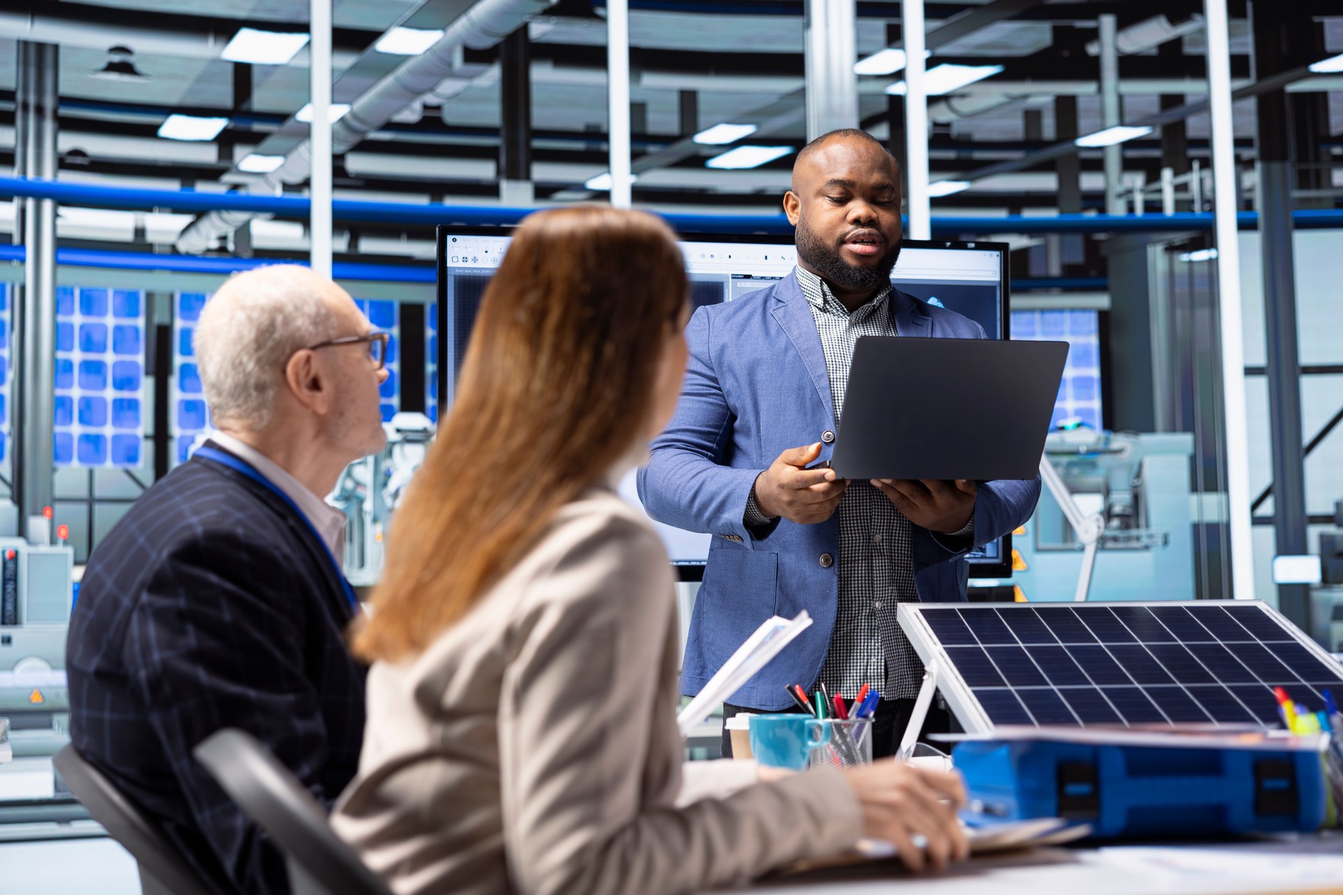 Empresario en planta de paneles solares mira datos de inversión en notebook