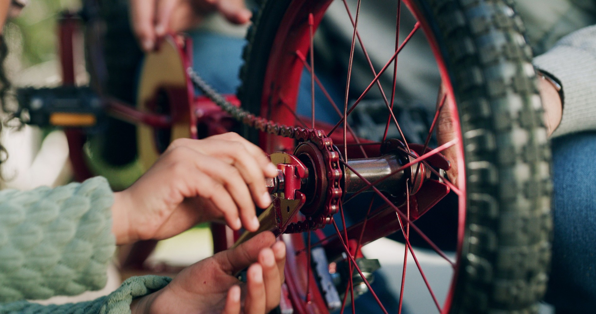 Manos, reparación de bicicletas y ayuda en el parque con inspección de seguridad, rueda o cadena para montar en verano. Personas, bicicleta y mantenimiento con equipo, al aire libre o aprendizaje con apoyo al transporte sostenible